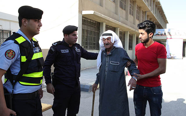 Police help an old man as he shows up at a ballot centre to take part in local elections in Amman on Tuesday (Petra photo)